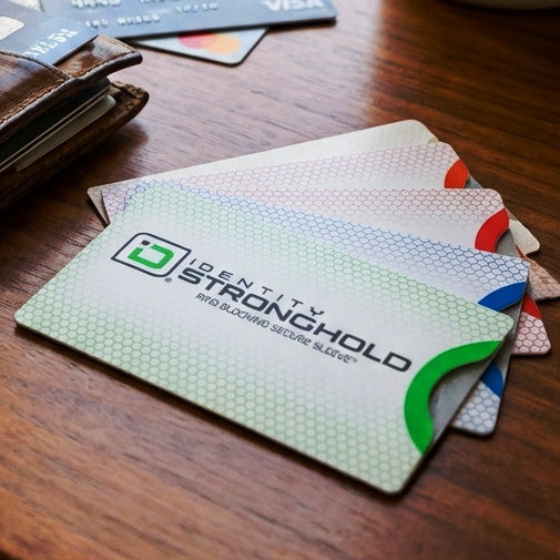 Identity Stronghold card protectors on a wooden surface with a wallet and cards in the background.