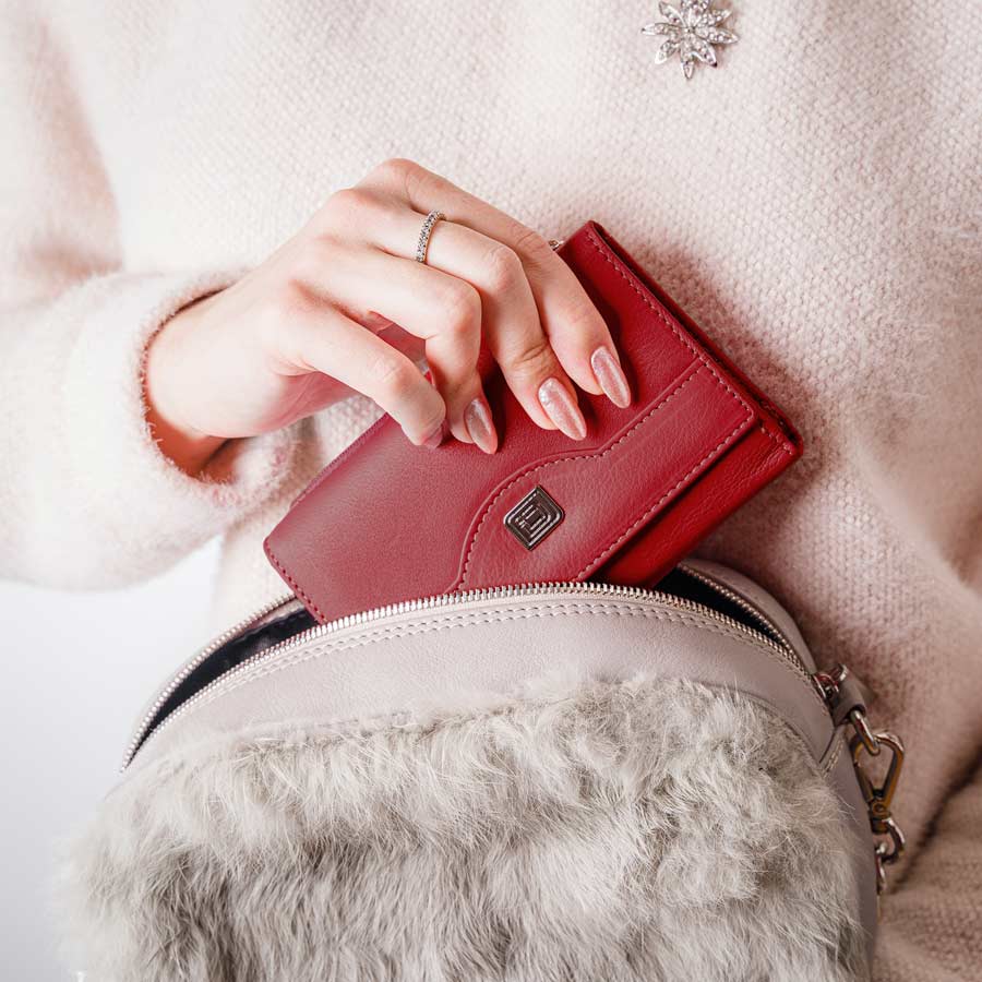 Red wallet held by a hand with a blurred background