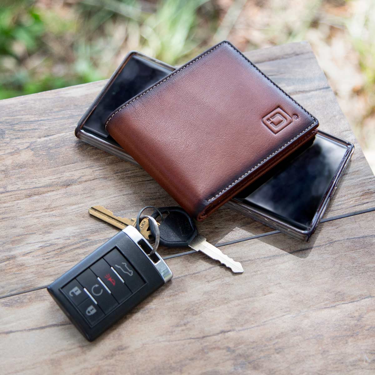 Brown leather wallet with keys and phone on a wooden surface